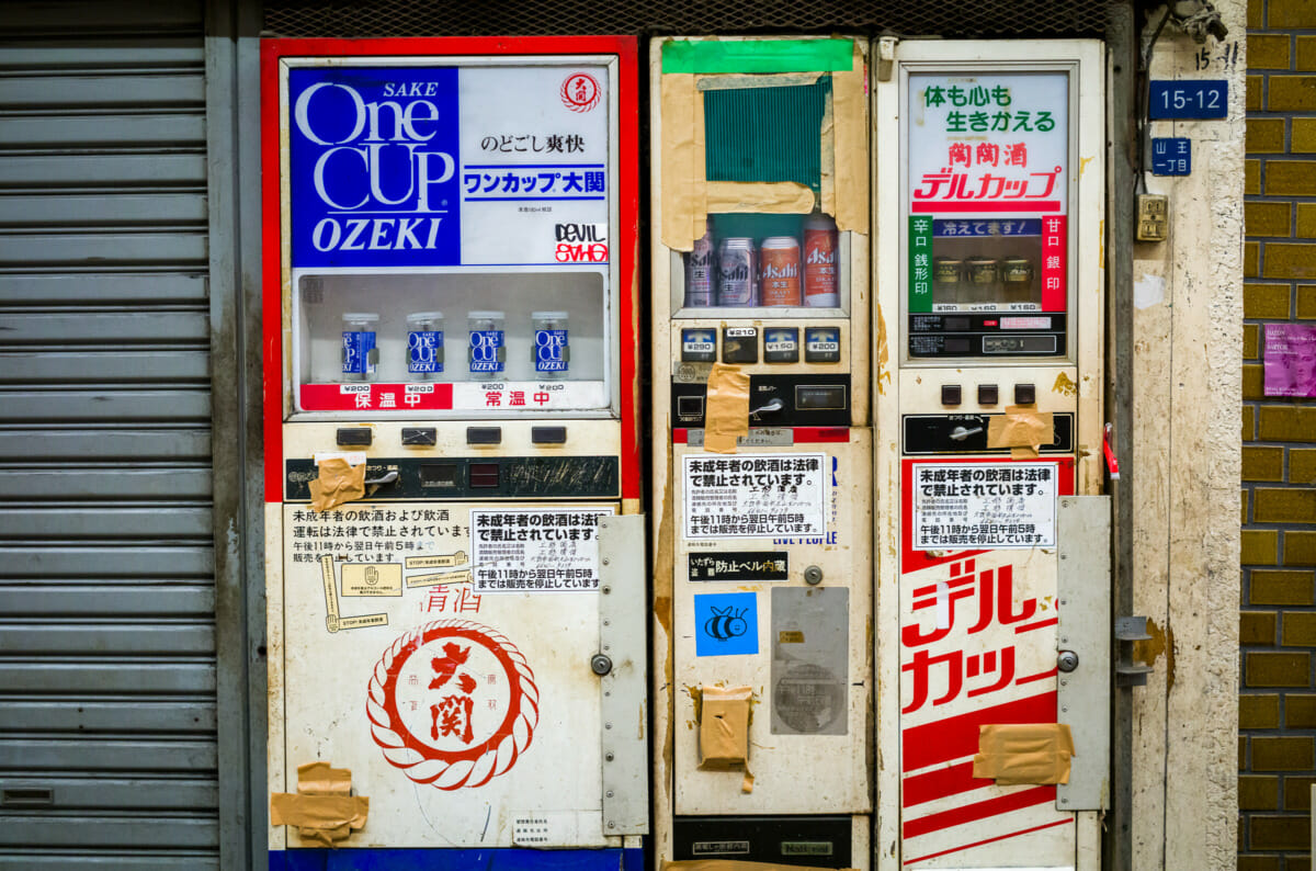 broken and taped up Japanese booze vending machines