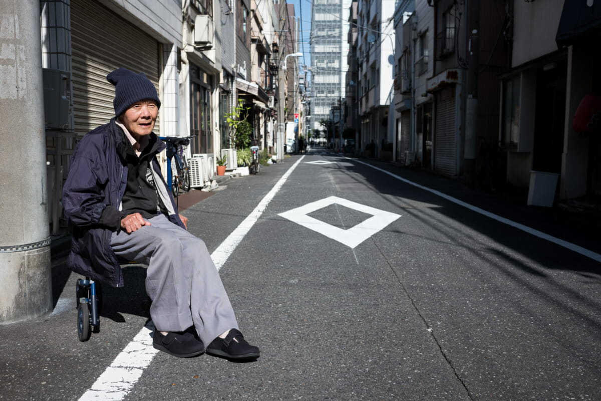 an old Japanese man sat out on a Tokyo side street