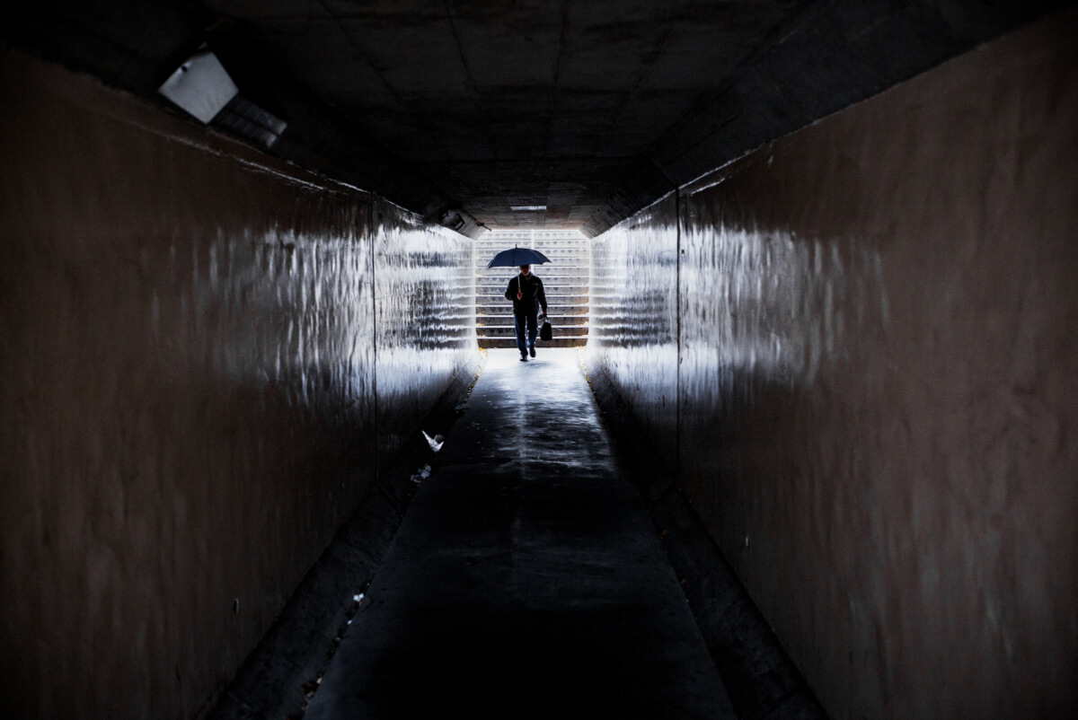 tokyo umbrella man in a dark passageway